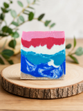 Tropical Flash Body Bar - handcrafted soap with bold pink, red, white, and blue tropical layers on a wood slice